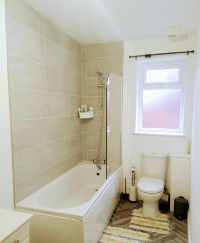 a bathroom with a tub and a toilet and a window at Sigma Central Apartment 2 in North Shields