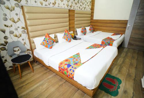 two beds in a room with white sheets and colorful pillows at Hotel Delhi Darshan Deluxe-By RSL Hospitality in New Delhi