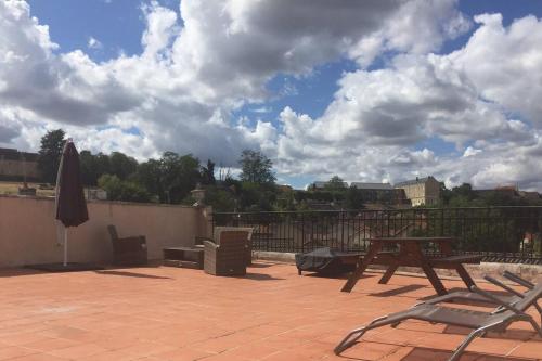 un patio con 2 sillas, una mesa y una sombrilla en 2 bed apartment fantastic roof terrace-town centre, en Montmorillon