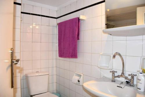uma casa de banho com um WC, um lavatório e uma toalha roxa em Colourful Apartment in AthensCity 1min from Subway em Atenas