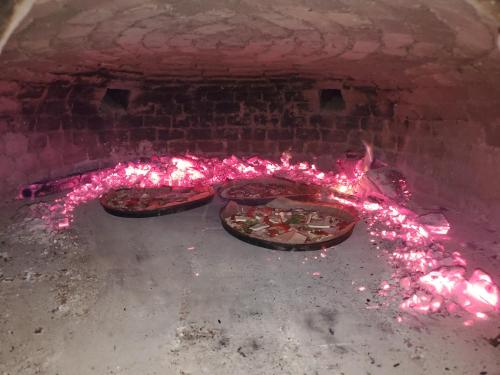 two pizzas in a brick oven with pink lights at Pensiunea Grosspold in Miercurea Sibiului