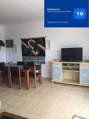 a living room with a table and a tv at Apartamento Guaruja Pitangueiras in Guarujá