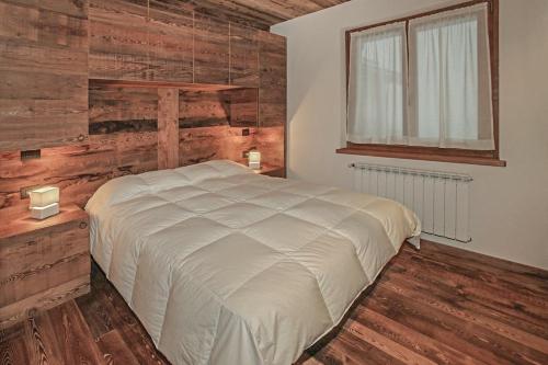 1 dormitorio con 1 cama y pared de madera en Snowflake Appartamenti Jouvenceaux en Sauze dʼOulx