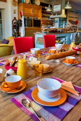 una mesa de madera con tazas y platos. en Villa Limonade, maison d'hotes, en Olonzac
