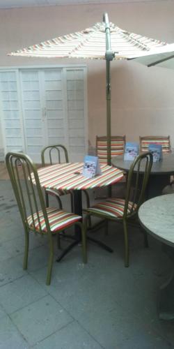 a table and chairs with an umbrella on a patio at pousadavaledasaguas in Foz do Iguaçu