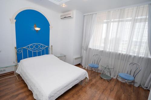 a bedroom with a bed and two blue chairs at Hotel Piano in Kyiv
