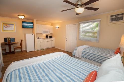a bedroom with two beds and a kitchen at Cedar Cove Resort & Cottages in Holmes Beach