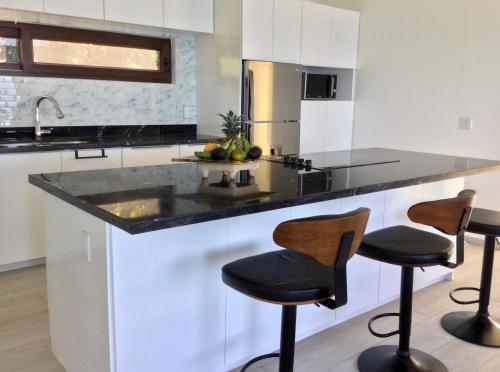 a kitchen with a counter and two stools in it at Stunning Turquoise Views From This 2 Bedroom, 2 Bath Home,,, in French Harbour