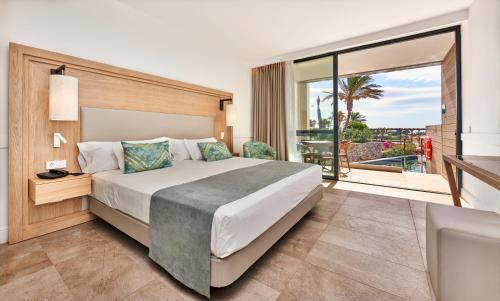 a bedroom with a large bed and a balcony at Insotel Punta Prima Resort in Punta Prima