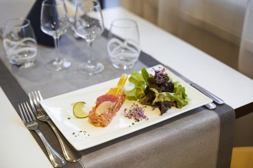 a plate of food on a table with wine glasses at Kyriad Le Mans Est in Le Mans