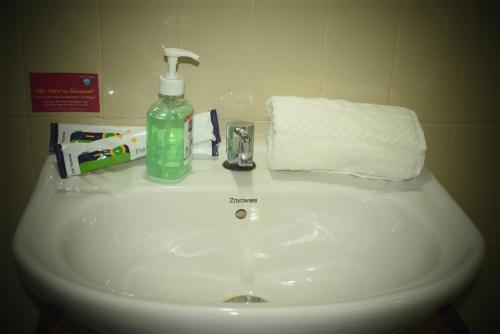 a bathroom sink with a bottle of soap and a towel at Reunion Villa in Udupi