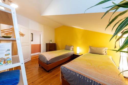 a bedroom with two beds and a yellow wall at Contador Mor Rooms and Apartments in Lisbon