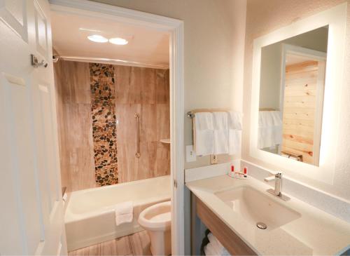 a bathroom with a sink and a toilet and a mirror at Baymont by Wyndham Gatlinburg On The River in Gatlinburg