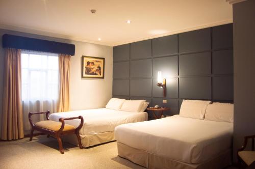 a hotel room with two beds and a chair at Hotel Carvallo in Cuenca