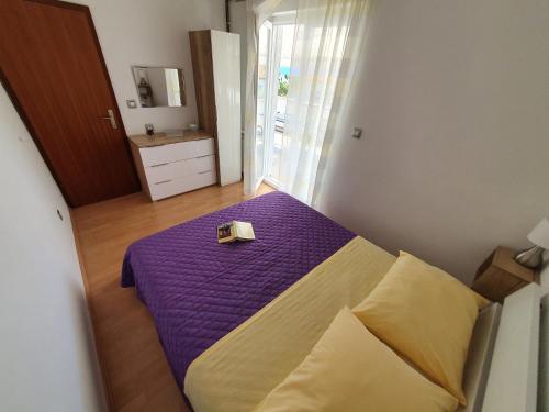 um quarto com uma cama roxa com uma caixa em Apartmani Alta em Krk