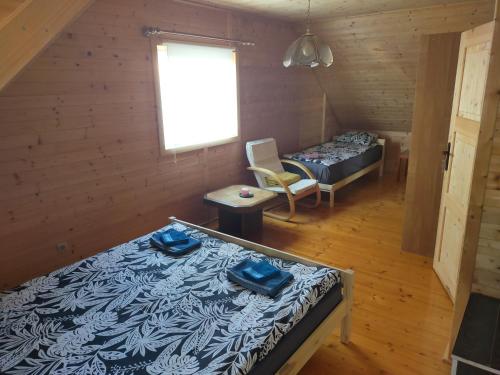 a room with two beds and a chair and a window at Drewniany domek w Otominie in Otomin