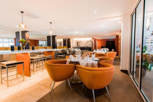 un restaurante con sillas naranjas y un bar en Baobab Tree Hôtel & Spa, en Mahajanga