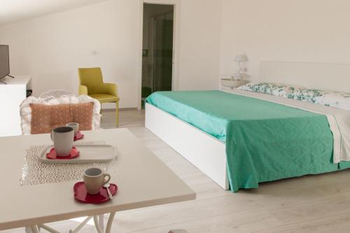 a bedroom with a bed with a green blanket and a table at Arco Fiorito in Cittadella del Capo