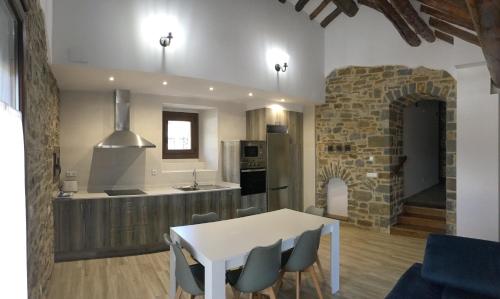 a kitchen with a white table and chairs in a room at Apartamentos Bajo Peña Apartamentos Sanlorien in El Pueyo de Araguás