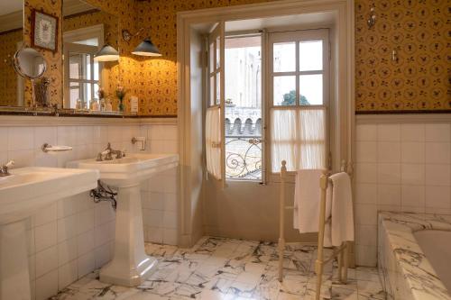 une salle de bain avec deux lavabos et une fenêtre dans l'établissement La Mirande, à Avignon