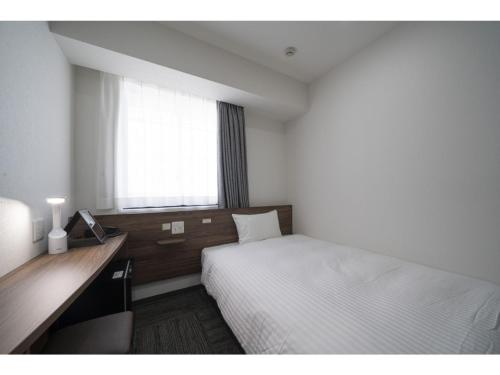 a bedroom with a bed and a desk and a window at R&B Hotel Sendai Higashiguchi - Vacation STAY 14646v in Sendai
