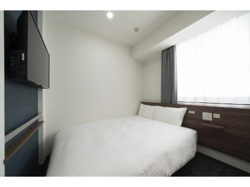 um quarto com uma cama branca e uma janela em R&B Hotel Sendai Higashiguchi - Vacation STAY 14656v em Sendai