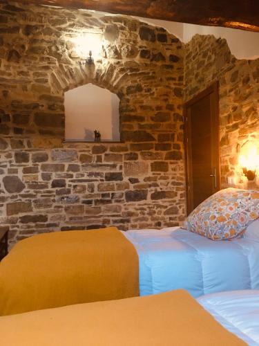 a bedroom with two beds and a stone wall at Apartamentos Bajo Peña Apartamentos Sanlorien in El Pueyo de Araguás
