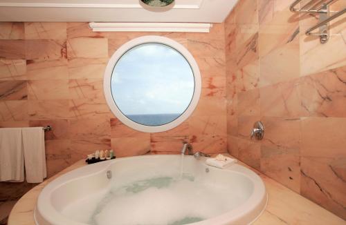 
a white bath tub sitting under a window in a bathroom at Insotel Hotel Formentera Playa in Playa Migjorn
