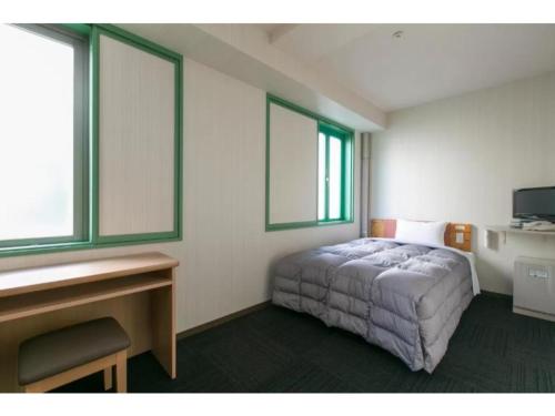 a bedroom with a bed and a desk and two windows at R&B Hotel Nagoya Nishiki - Vacation STAY 15165v in Nagoya