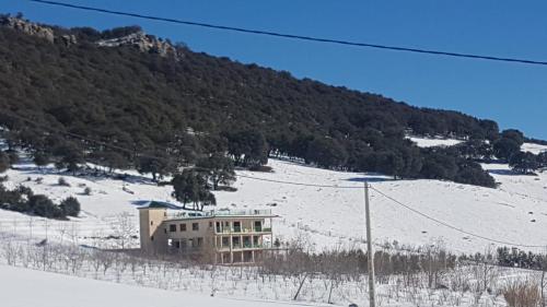a building sitting in the snow in front of a mountain at Le Chêne d´Azrou in Azrou