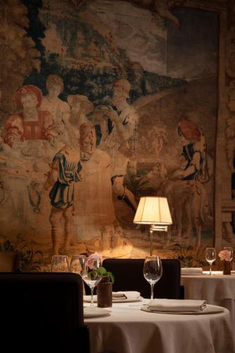 a table with wine glasses and a painting on the wall at La Mirande in Avignon