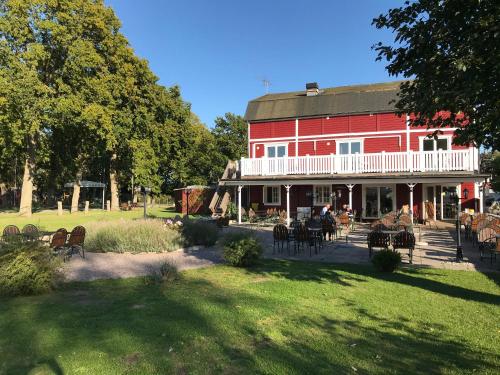 a large red house with people sitting on the porch at Hotell Magasin 1 in Mörbylånga