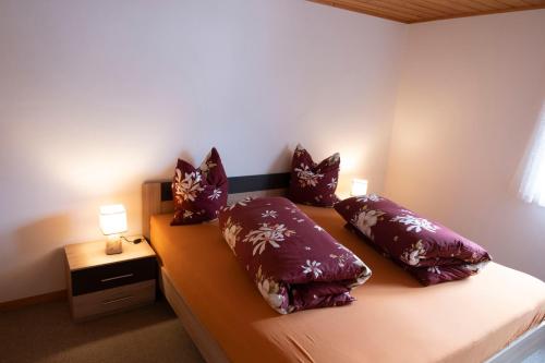 ein Schlafzimmer mit einem Bett mit lila Kissen darauf in der Unterkunft Chasa Archas in Sent