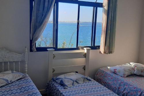 a bedroom with a window with a view of the ocean at Hospedagem Praia da Costa in Vila Velha