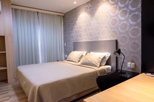 a bedroom with a bed and a desk with a lamp at Hotel Executive Arrey in Teresina