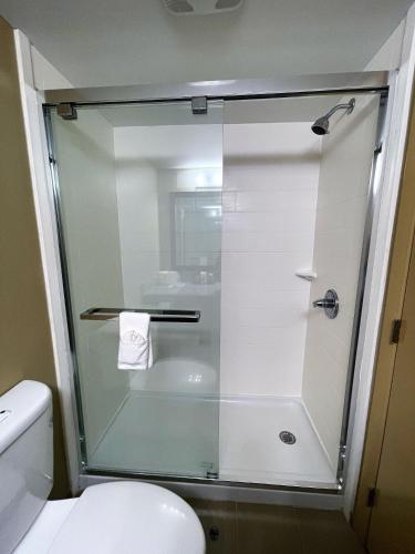 a glass shower in a bathroom with a toilet at Super 8 by Wyndham Raleigh North East in Raleigh
