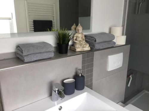 ein Badezimmer mit einem Waschbecken, einem Spiegel und Handtüchern in der Unterkunft Ferienapartment Kischa in Scharbeutz