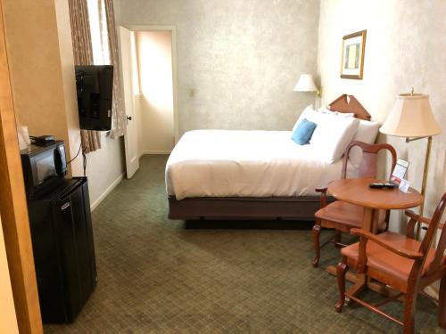 a hotel room with a bed and a table and a television at Stearns Hotel in Ludington