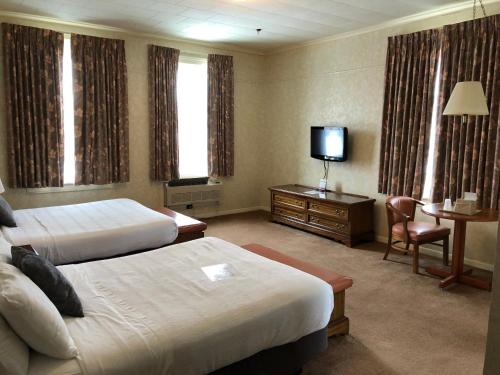 Cette chambre comprend deux lits et une télévision. dans l'établissement Stearns Hotel, à Ludington