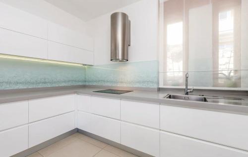uma cozinha com armários brancos e um lavatório em Apartman Villa Pećine em Rijeka