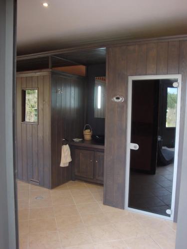 - une cuisine avec des murs en bois et une porte menant à une chambre dans l'établissement Domaine de Gaudon, à Ceilloux