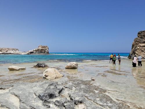 a group of people walking on the beach at شاليهات بورتو مطروح فيو بحر Porto Matrouh Sea View Families Only in Marsa Matruh