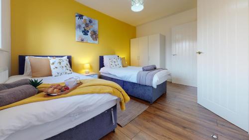a bedroom with two beds with yellow walls and wooden floors at SRK Serviced Accommodation, 2 Bedroom Private Apartment, Business, Leisure, Contractors in Peterborough