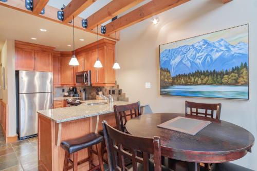 a kitchen with a table and chairs and a kitchen with a refrigerator at Wildwood Lodge by Outpost Whistler in Whistler