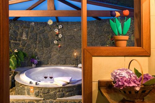 a bath tub in a room with a stone wall at Hotel Bühler in Visconde De Maua