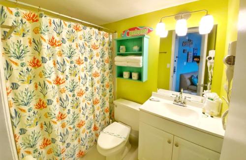 a bathroom with a shower curtain and a toilet and a sink at Harbour Beach Resort Studios! in Daytona Beach