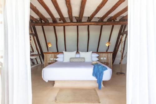 a bedroom with a bed with white sheets and pillows at Hotel Villas Flamingos in Holbox Island