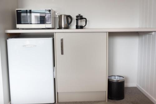 a kitchen with two refrigerators under a counter with a microwave at Raglan Sunset Motel and Conference Venue in Raglan