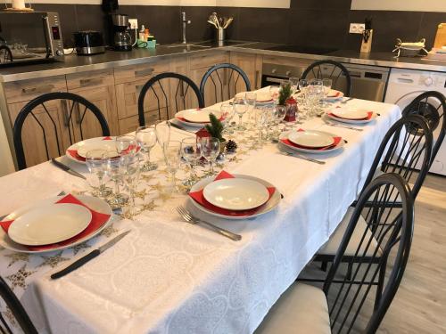 - une table à manger avec une nappe et des chaises blanches dans l'établissement LE DAUPHIN - 3 chambres - 8 personnes - proximité plage, à Bréhal