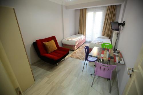 uma sala de estar com uma cadeira vermelha e uma mesa em Bella Suit Apart Hotel em Isparta